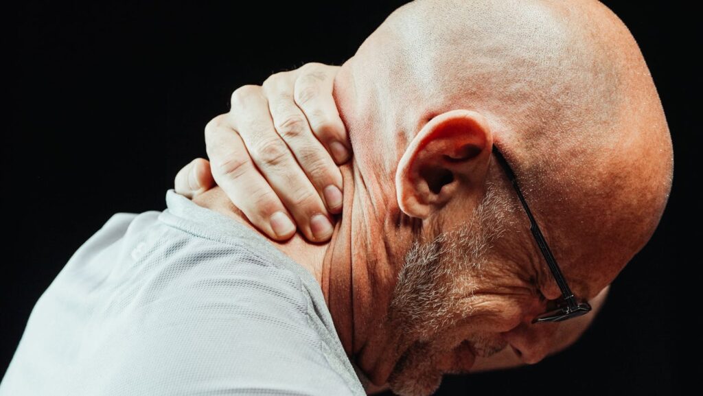 Side view of senior man holding neck with visible discomfort, highlighting neck pain relief.